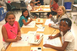 Clockwise around the table, starting bottom left, Sarah Hutchins, Kaia Lee-Espiritu, Olivia Hall and Alysa Hawkins enjoy their brush painting class at STARTALK. 