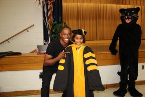 Dr. Adolf Brown helps Parkway Elementary School student Tashani Motley try on a graduation look. 
