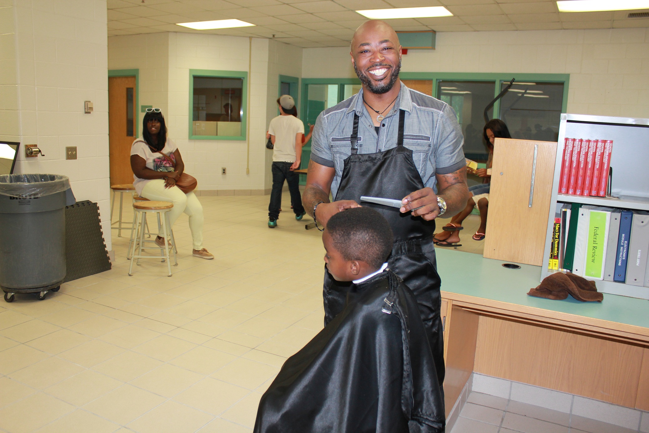 Lefenton “Kenny” Ellis from Lefenton’s Barber Shop in Virginia Beach returned as a volunteer again this year not only because he had a great time last year, but he wanted to help to make sure students had the “edge” when they walk through the front door of the schools on that special first day. It’s appears that kindergartner Kieran L. can’t wait for school to start. “I want to play with my friends and I want to learn to read,” he said as he held up a new book he was just given from the Yardigans Series.