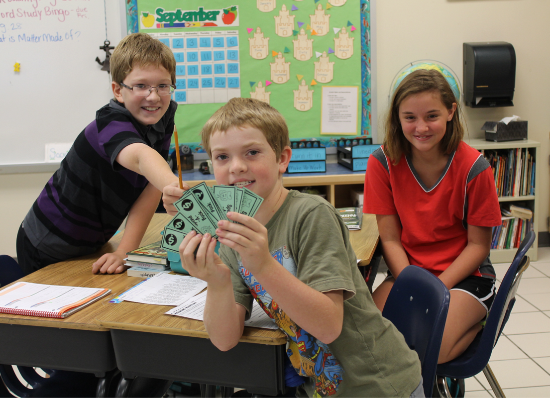  Jacob Kaneiss, center, shows off all of his investor money to classmates Brianna Middleton and Alexander Krell.  